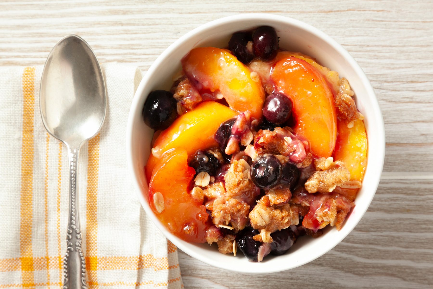 Bowl of Peach Blueberry Crisp on a wooden table