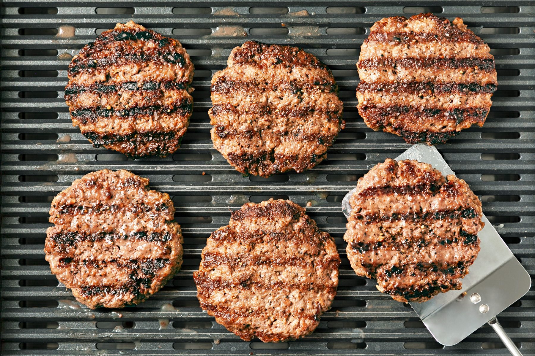 Grilling the beef patties until cooked on both sides by flipping them