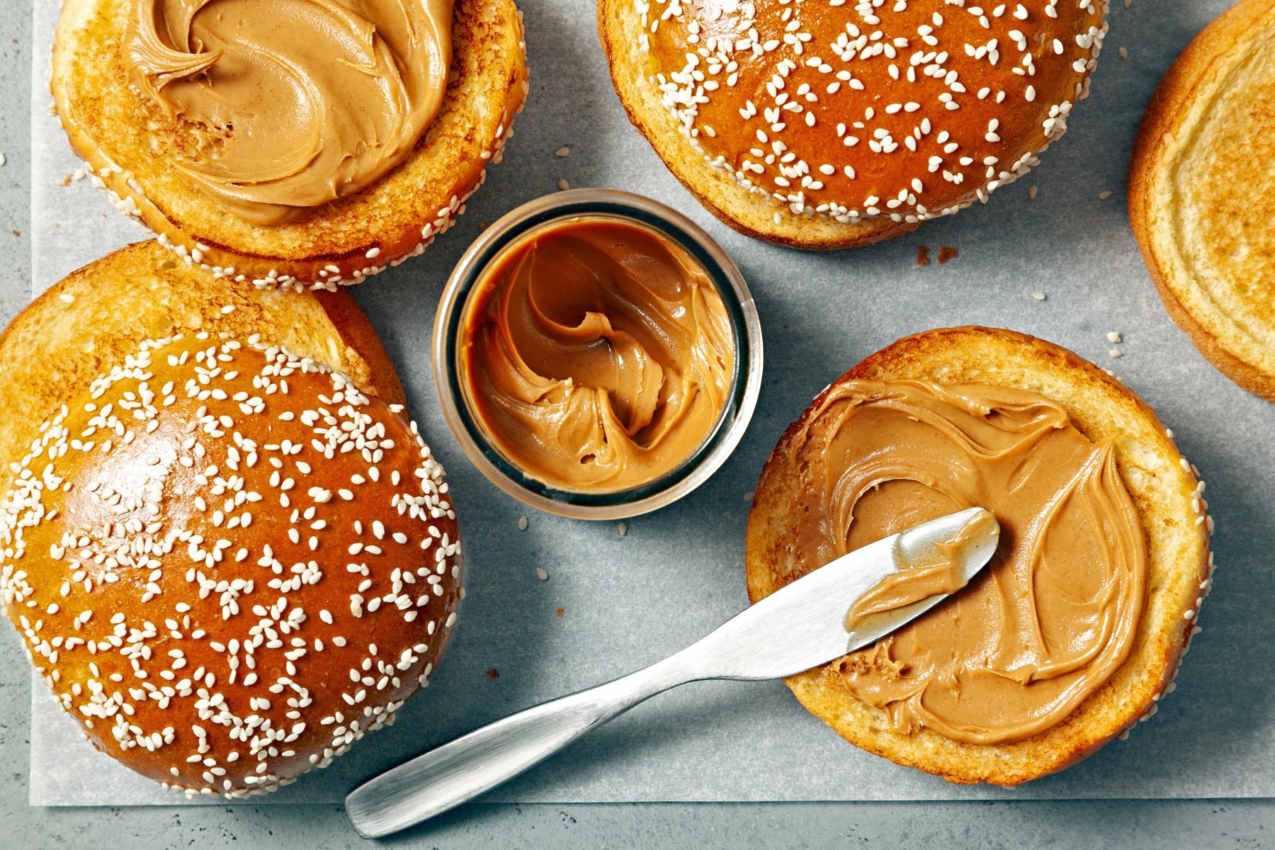 Top view of spreading peanut butter on burger bun