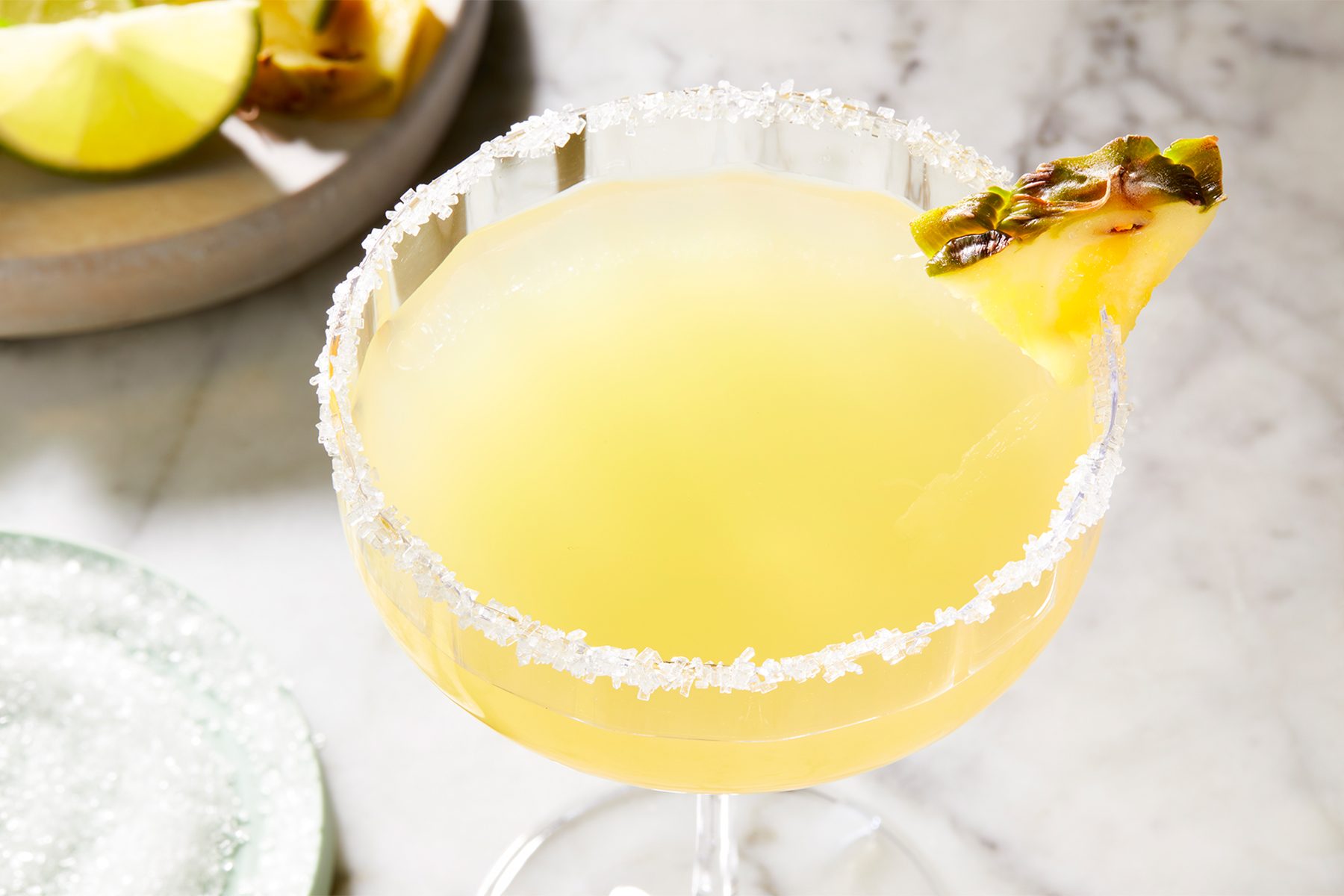 high angle shot of pineapple margarita in a cocktail glass garnished with lime wedge