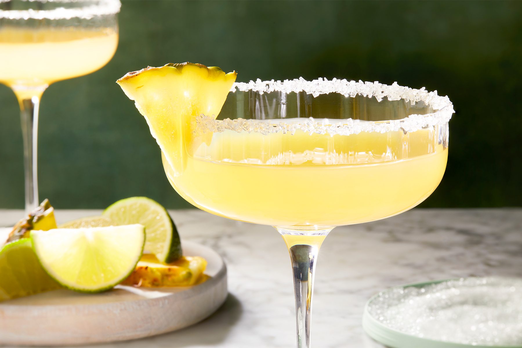 wide shot of pineapple margarita in a coctail glass garnished with lime wedge