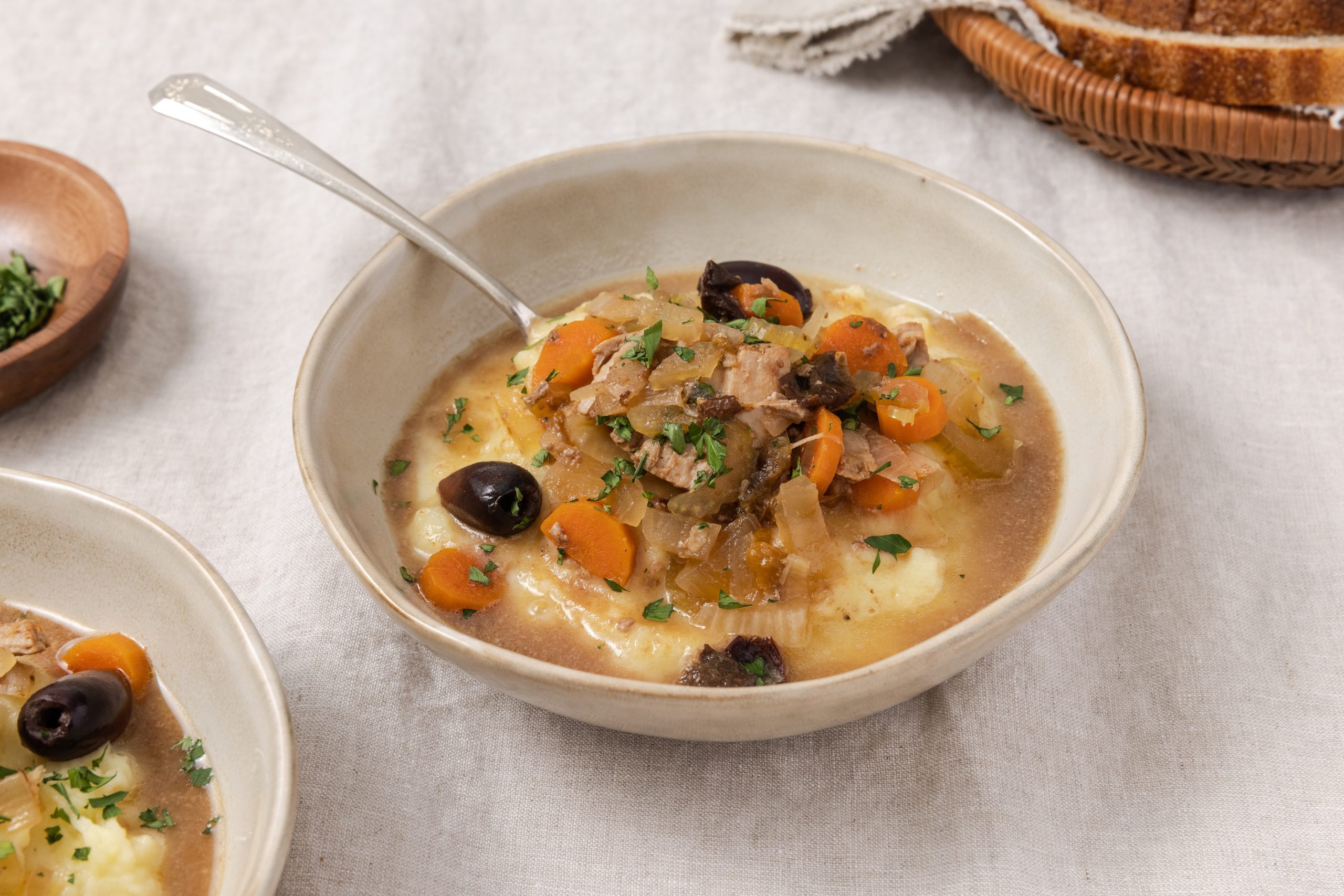 Pork stew served in bowl with mashed potato and spoon.