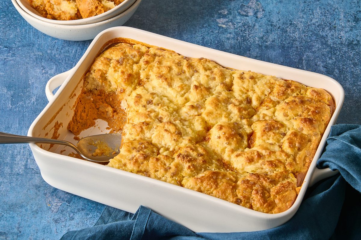 Angled shot of pumpkin cobbler in a dish with a portion scooped out