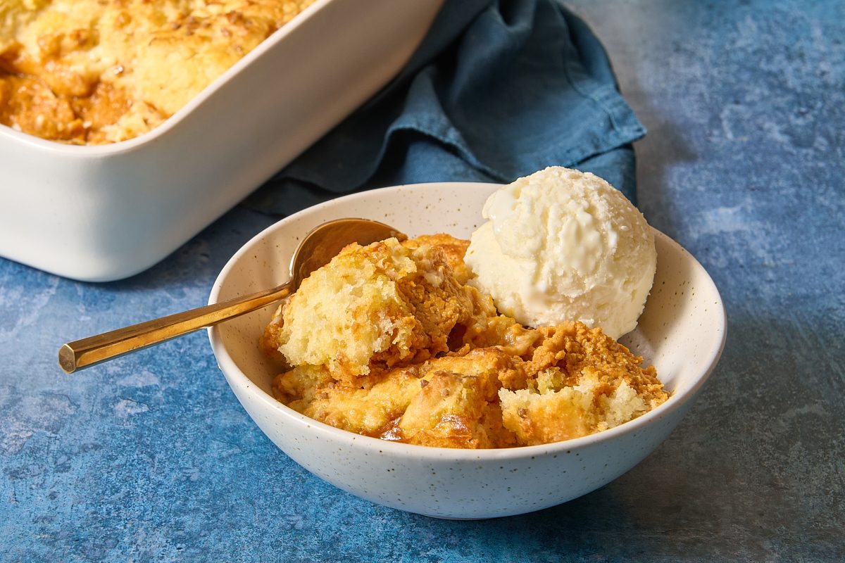 Portion of pumpkin cobbler in a bowl with ice cream