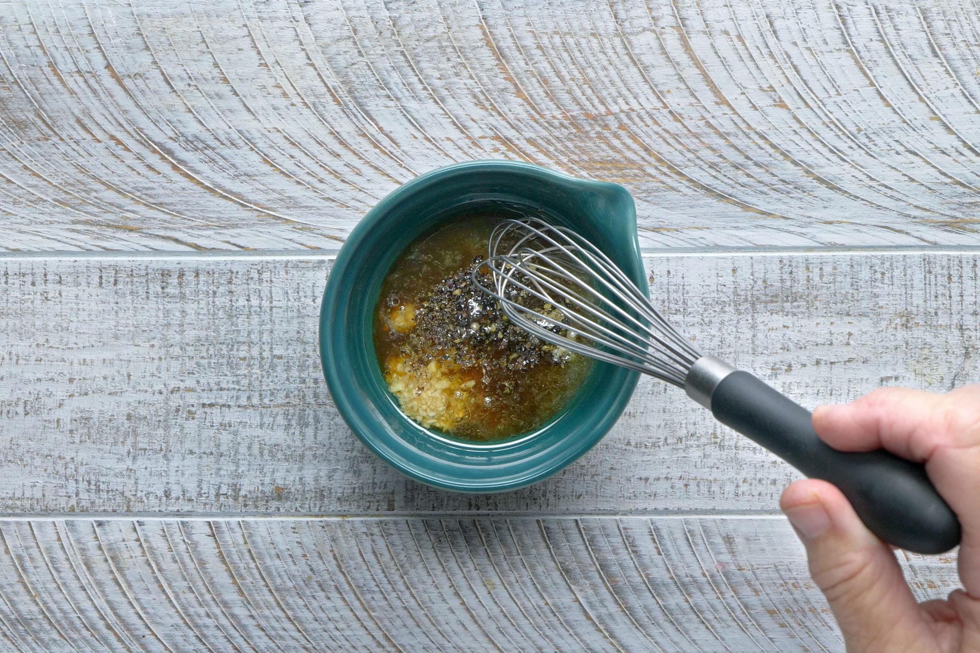 In a small bowl, whisk oil, lemon juice, vinegar, water, garlic, salt and pepper until blended; wooden background;