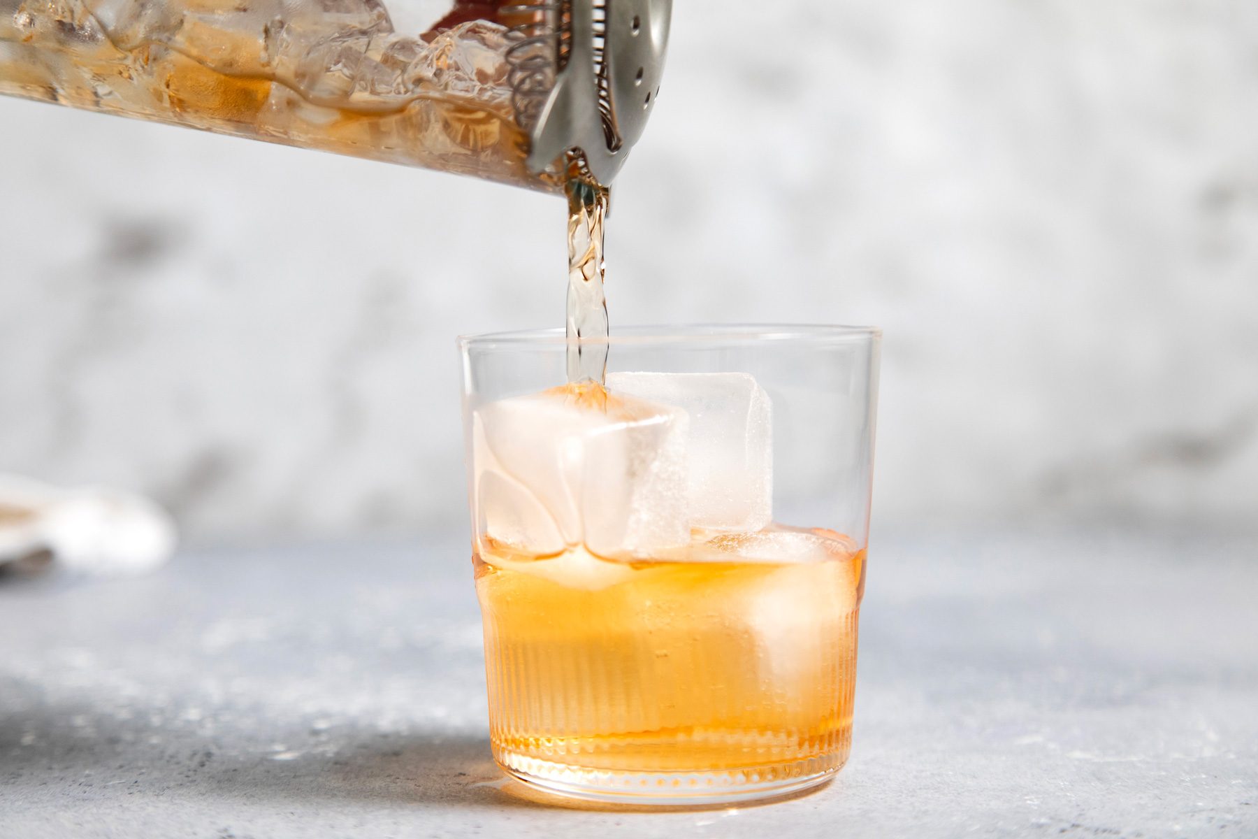 Pouring Rusty Nail into a glass with ice cubes