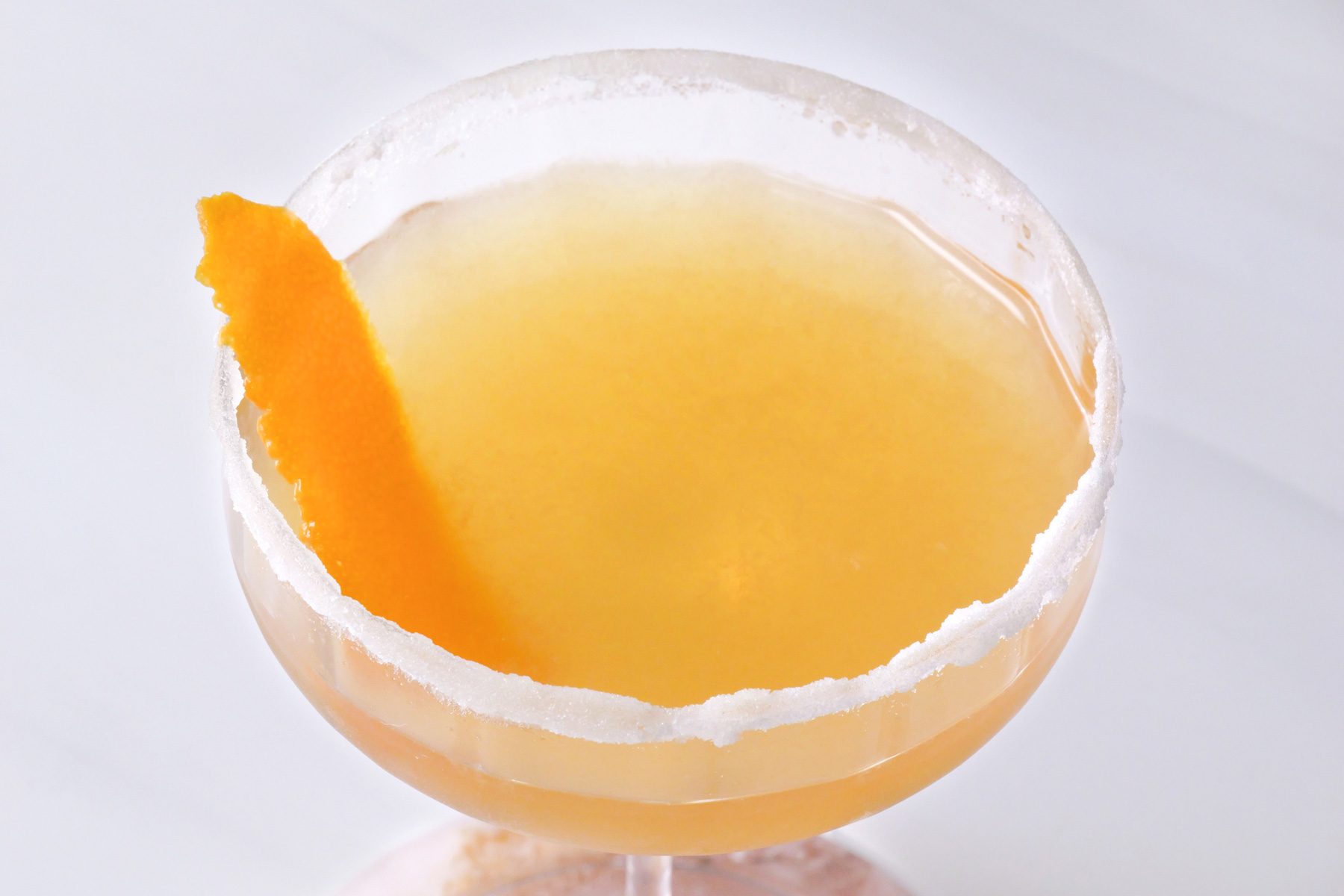 Close up of orange peel in the coupe glass with sidecar cocktail