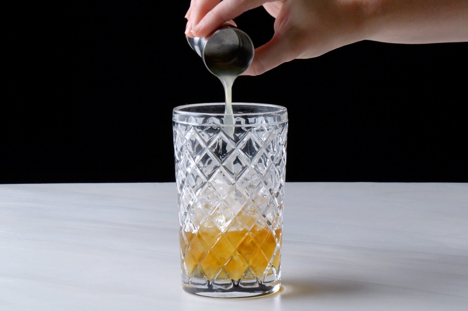 Pouring Cognac, Cointreau and lemon juice with ice in the cocktail shaker