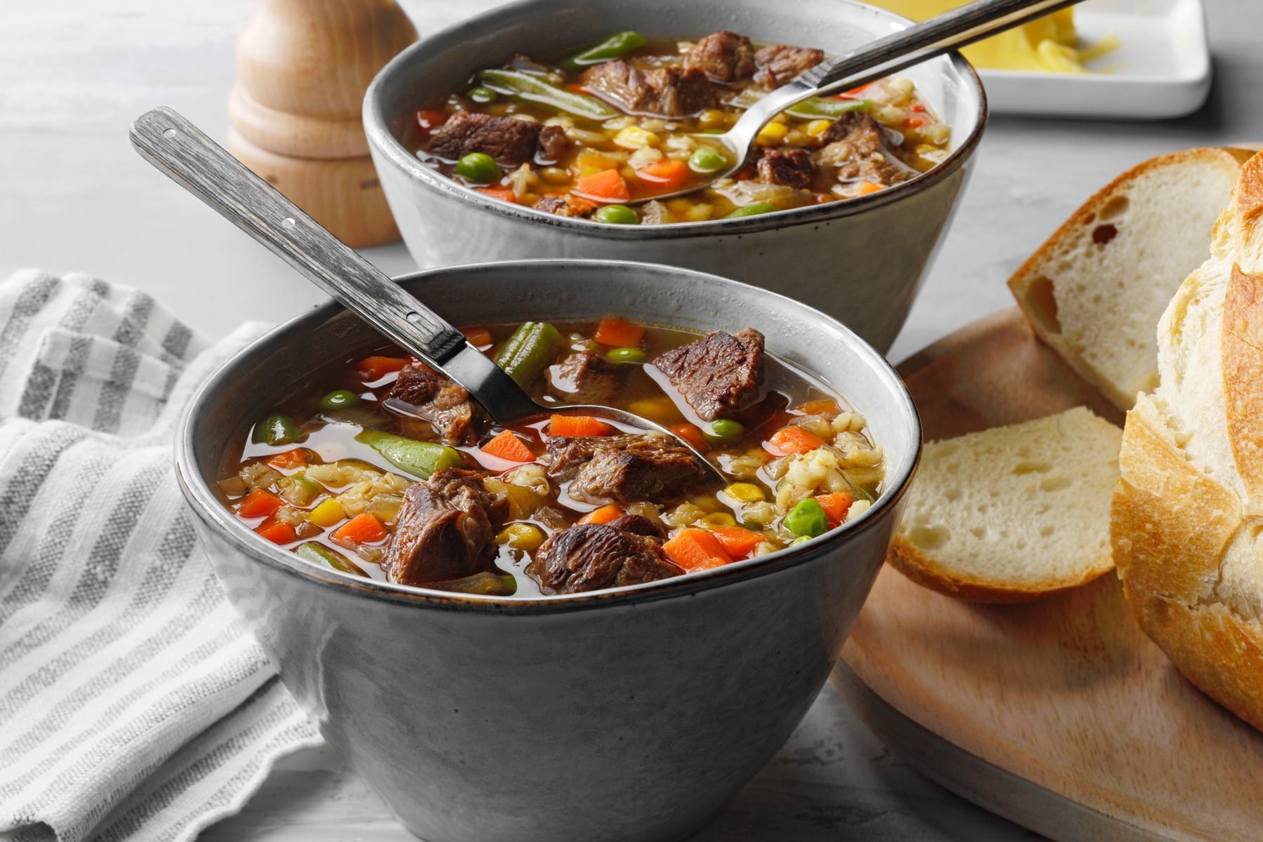 Slow Cooker Beef And Barley Soup in soup bowls served with bread