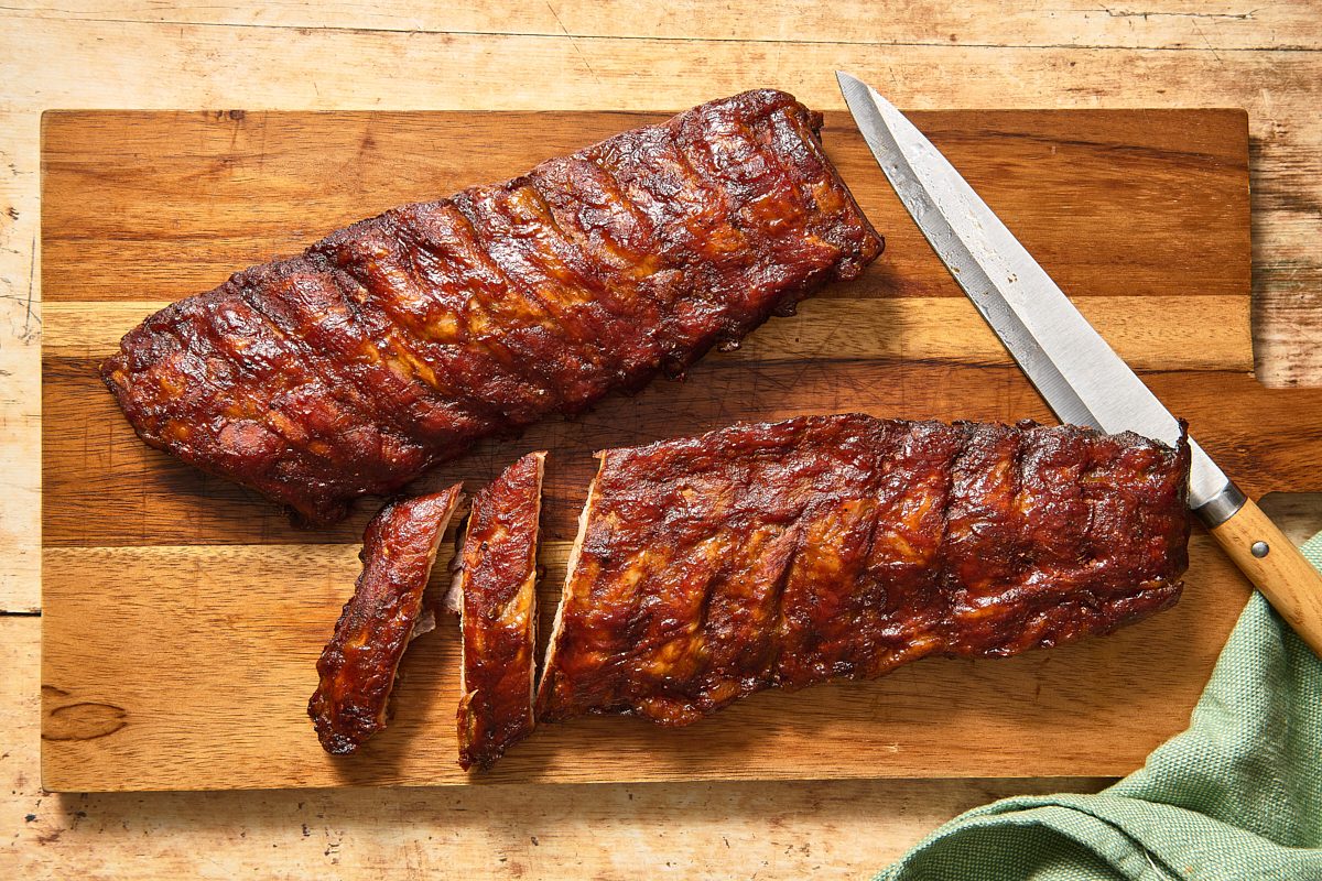 Smoked ribs on a cutting board with a knife