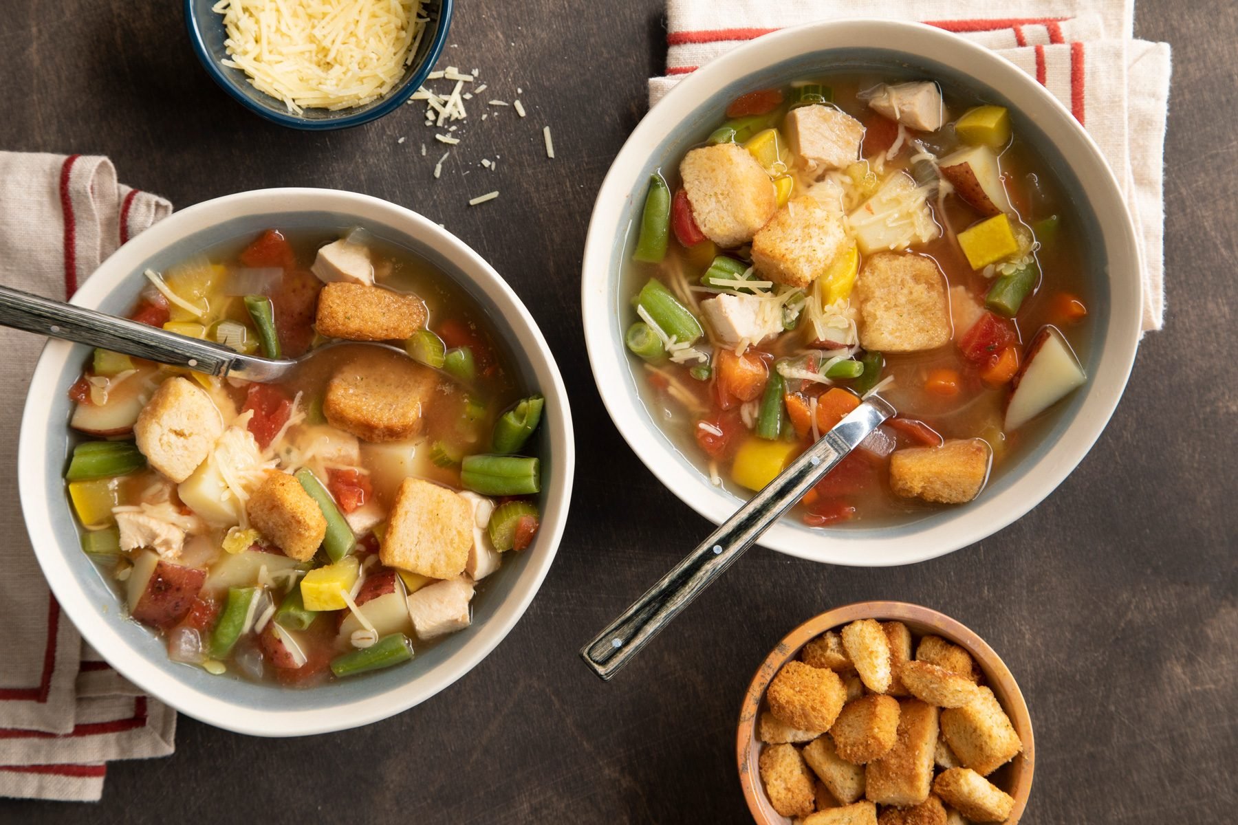 Two bowls of stone soup on a wooden background.