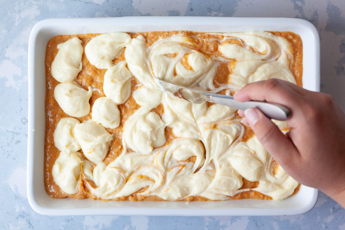 Step 3 of Taste of Home Sweet Potato Cheesecake Brownies is to spread the sweet potato mixture onto the crust and then dropping the cream cheese mixture in spoon-fuls on top before swirling with a knife