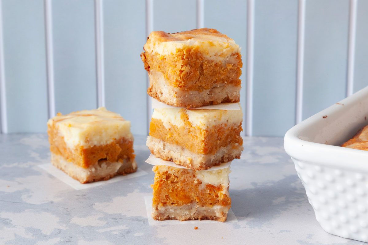 Close up of Taste of Home Sweet Potato Cheesecake Brownies in a white pan, cut into squares