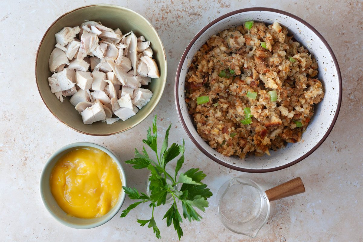 Taste of Home Turkey Stuffing Casserole ingredient shot inlcuding crem of chicken soup, cooked cubed turkey, parsley and leftover stuffing