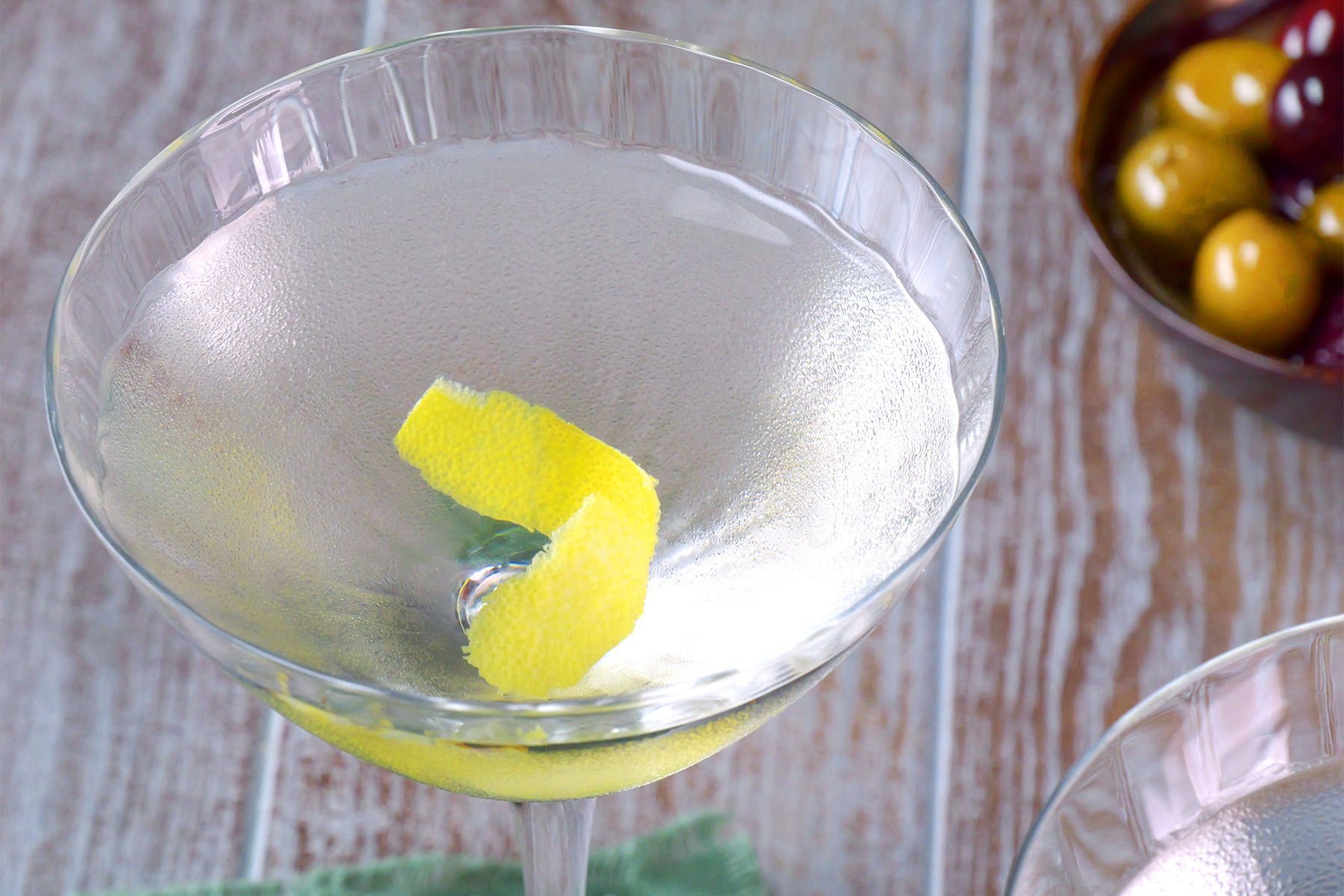 3/4th shot; close shot; wooden background; Vesper Martini served in martini glass with lemon peel inside it;