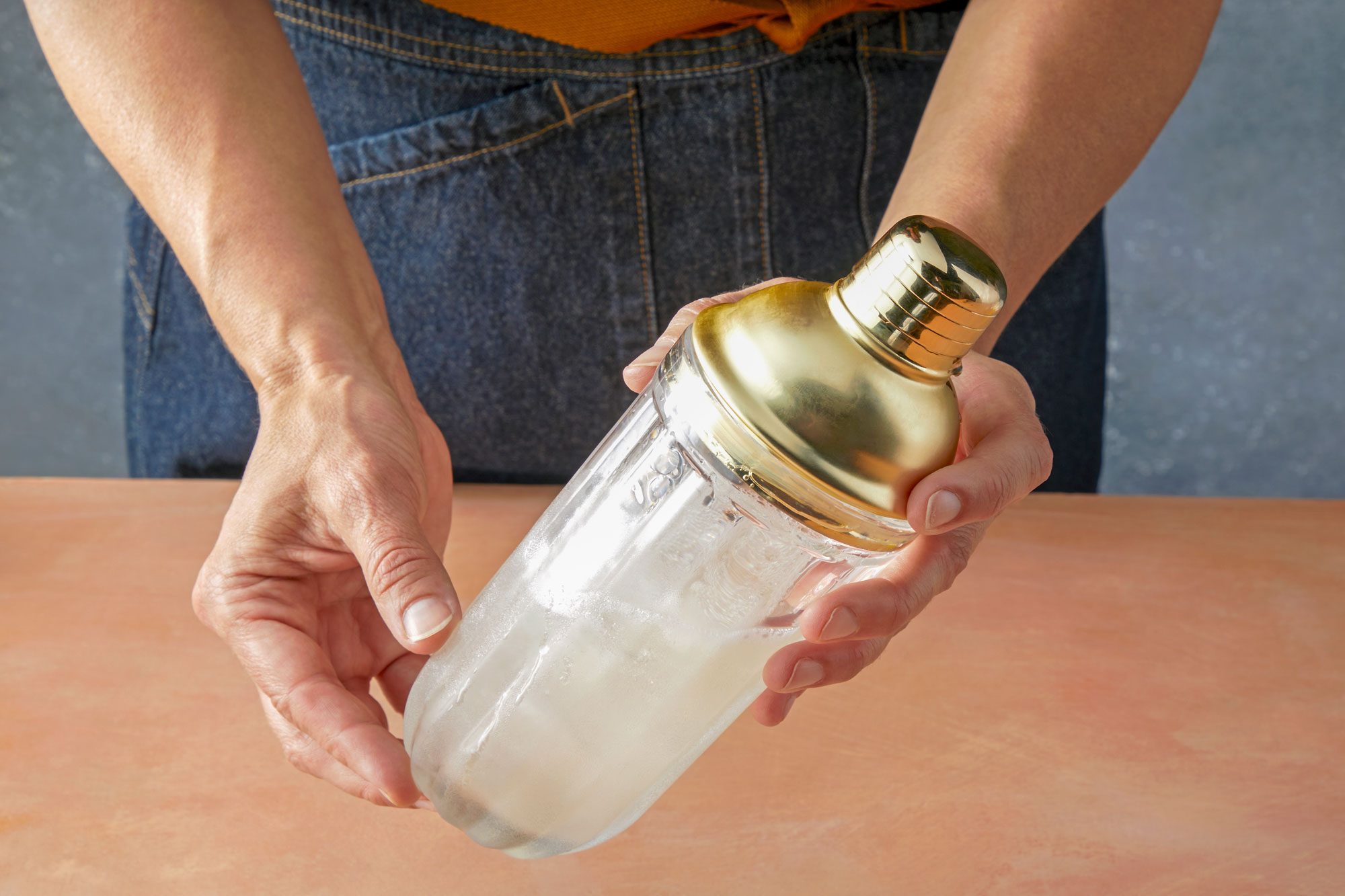 Table view shot of cover and shake until condensation form on outside of shaker; light orange background;