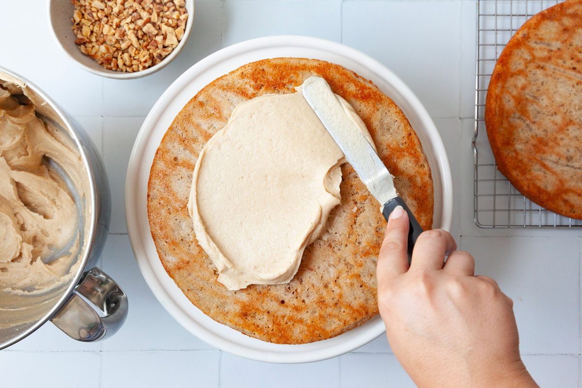 Step 7 of Taste of Home Apple Spice Cake is to assemble by frosting betwen the layers and on the outstide of the cake before pressing nuts into the top