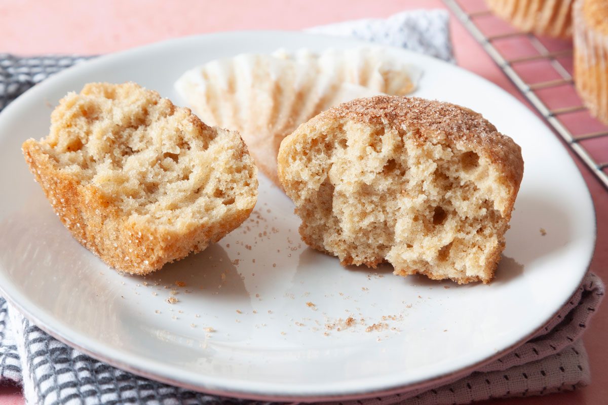 Close up of single Taste of Home Applesauce Muffin on plate, cooling rack in the background