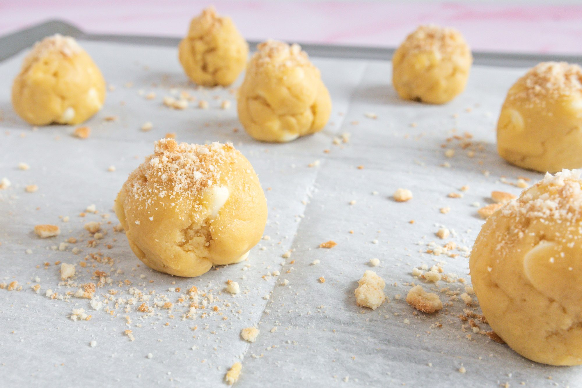 Close shot of shape dough into 1 inch balls; place on parchment-lined baking sheets; sprinkle with crushed wafers; bake until edges just begin to turn golden brown; pink texture surface;