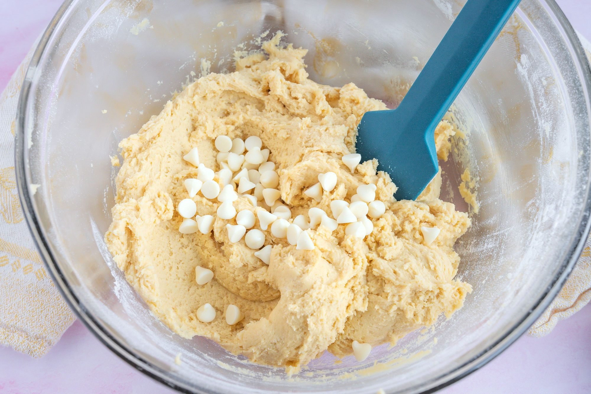 Overhead shot of gradually beat into creamed mixture; stir in chips; cover and refrigerate 30 minutes; blender; kitchen towel; pink texture surface;