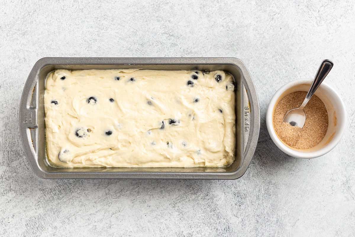 Taste of Home Blueberry Pound Cake recipe photo of the batter transfered to a loaf pan with a side of cinnamon sugar to top the batter.