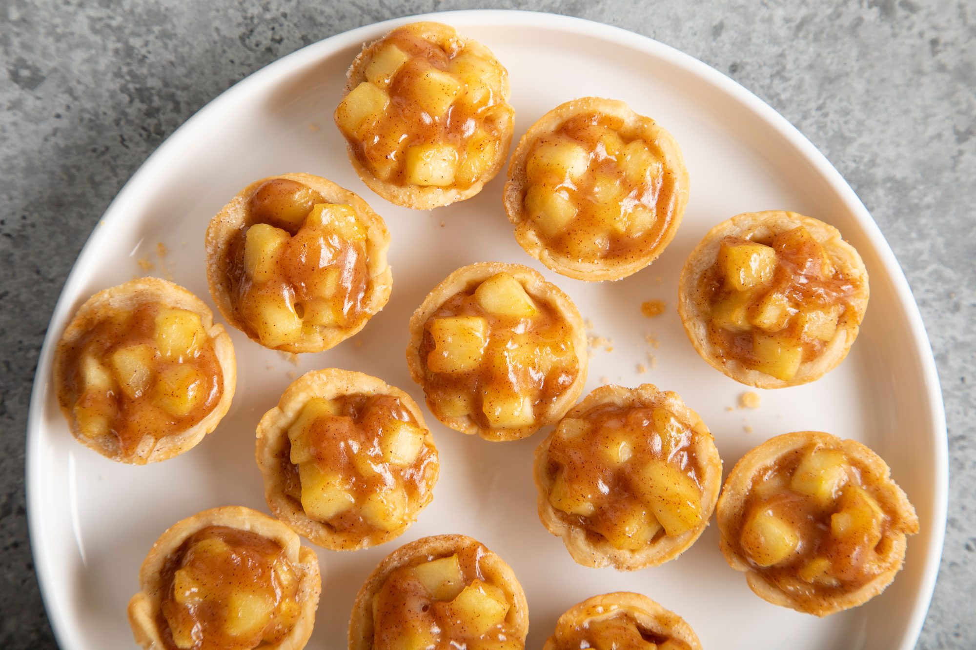 Caramel Apple Tartlets on a white ceramic plate on grey background