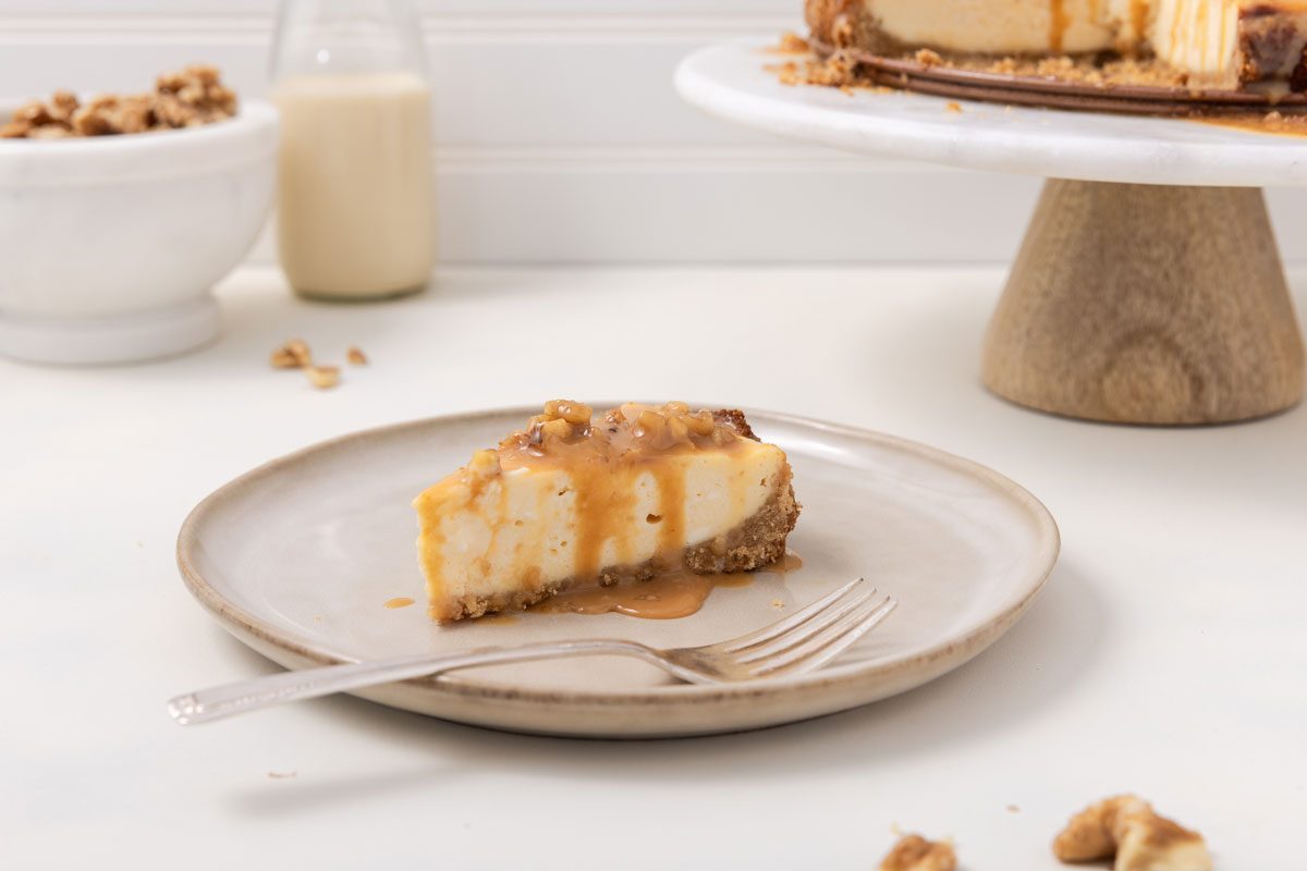 Cheesecake ready with caramel sauce on top on cake stand.