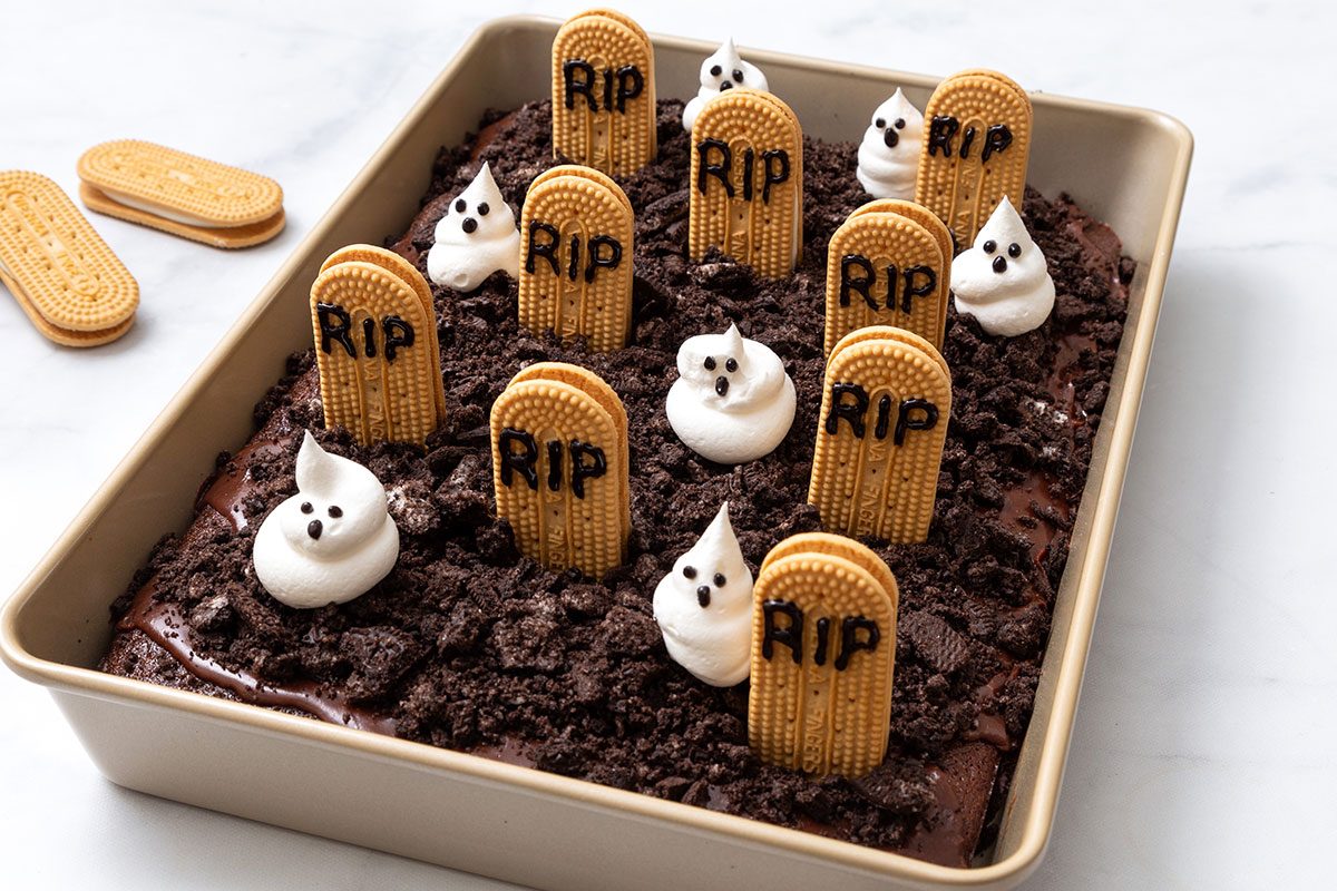 Cemetery Cake with cool whip ghosts and vanilla oval cookie graves in baked chocolate cake for step 4 for Cemetery Cake recipe for Taste of Home