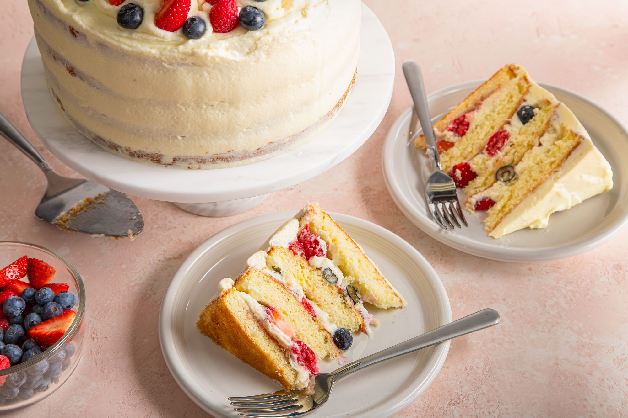 Chantilly cake on a marble cake stand; slices of Chantilly cake served on two plates with forks; pink texture background;