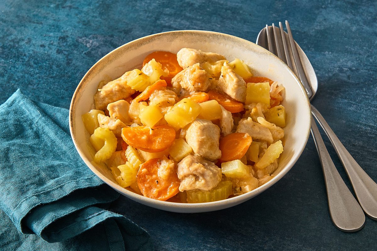 Chicken stew served in a bowl with a fork and spoon