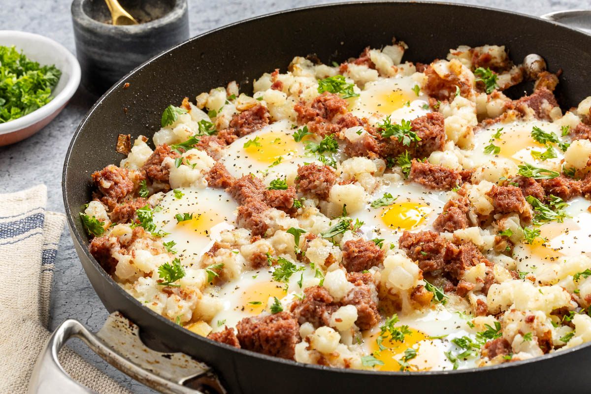 Taste Recipes Corned Beef Hash and Eggs recipe photo of the finished recipe in a skillet. 