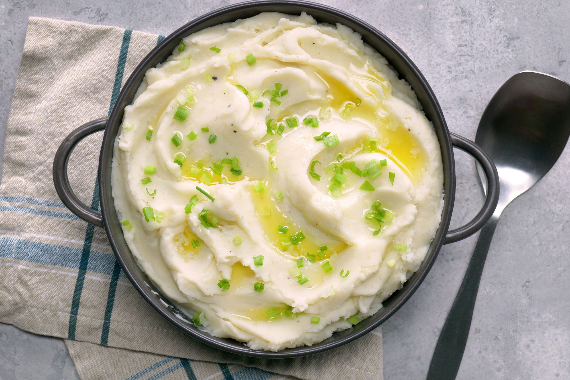 Creamy Mashed Potatoes in a stockpot sprinkled with green onion on top