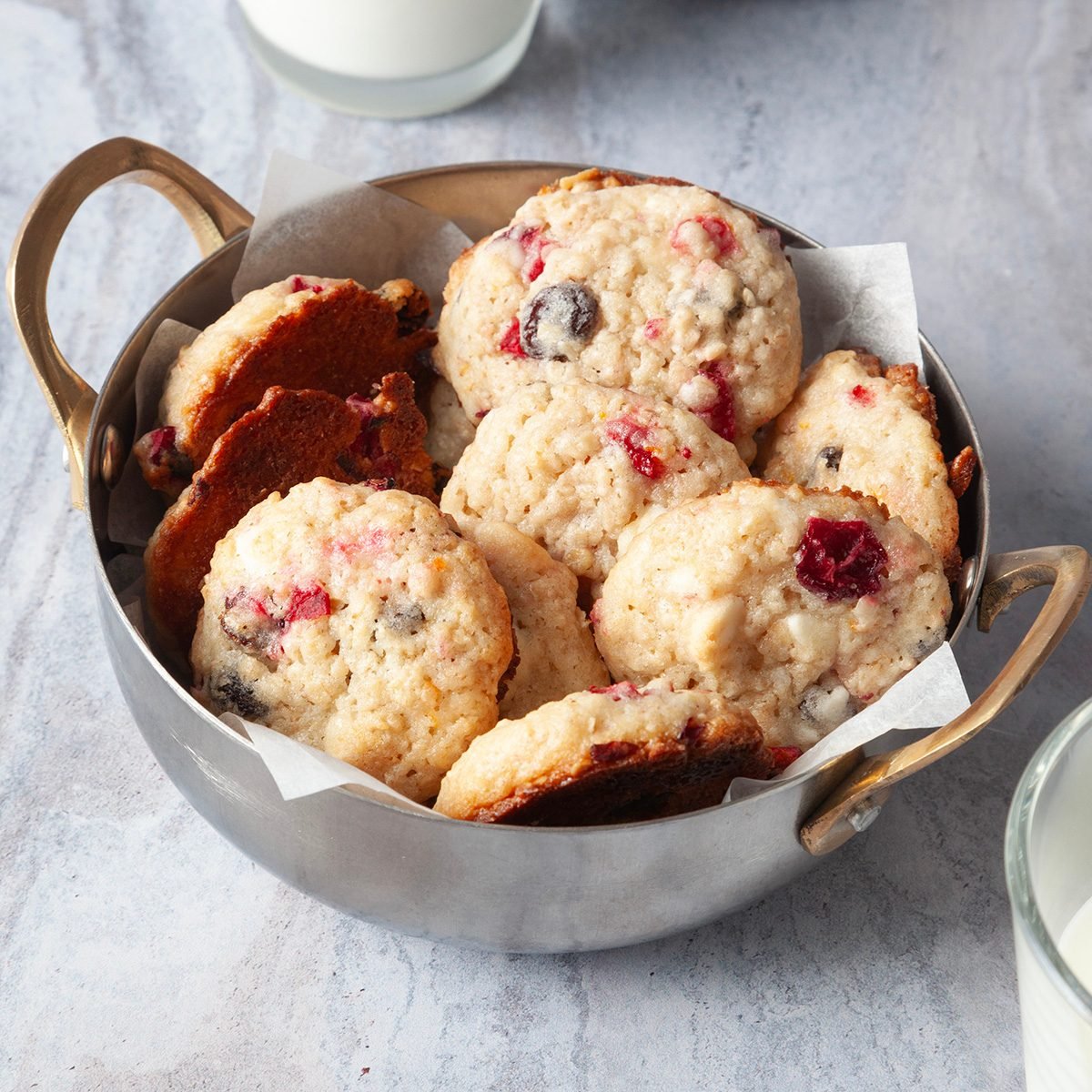 Full yield of Taste of Home Oatmeal Cranberry Cookies in a silver metal bowl with handles, milk glasses