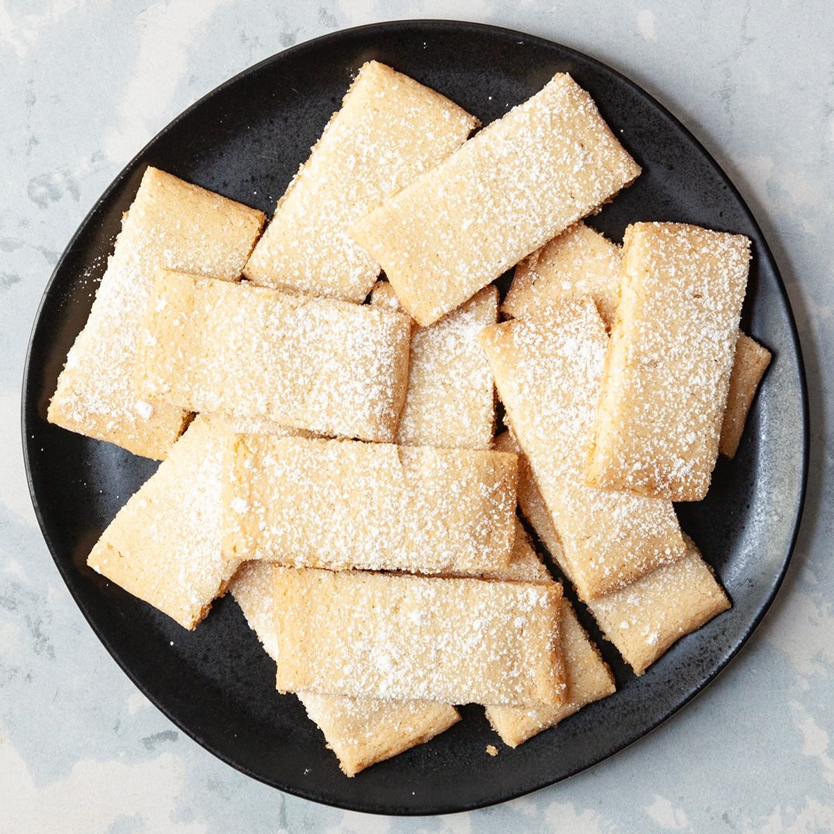 Taste of Home Swiesh cookies on a black plate and more cooling on a rack peaking in