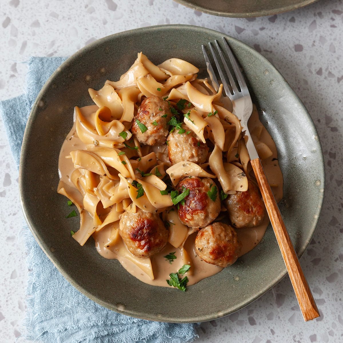 Single servings of Taste of Home Meatball Stroganoff on green plates, garnished with parsley