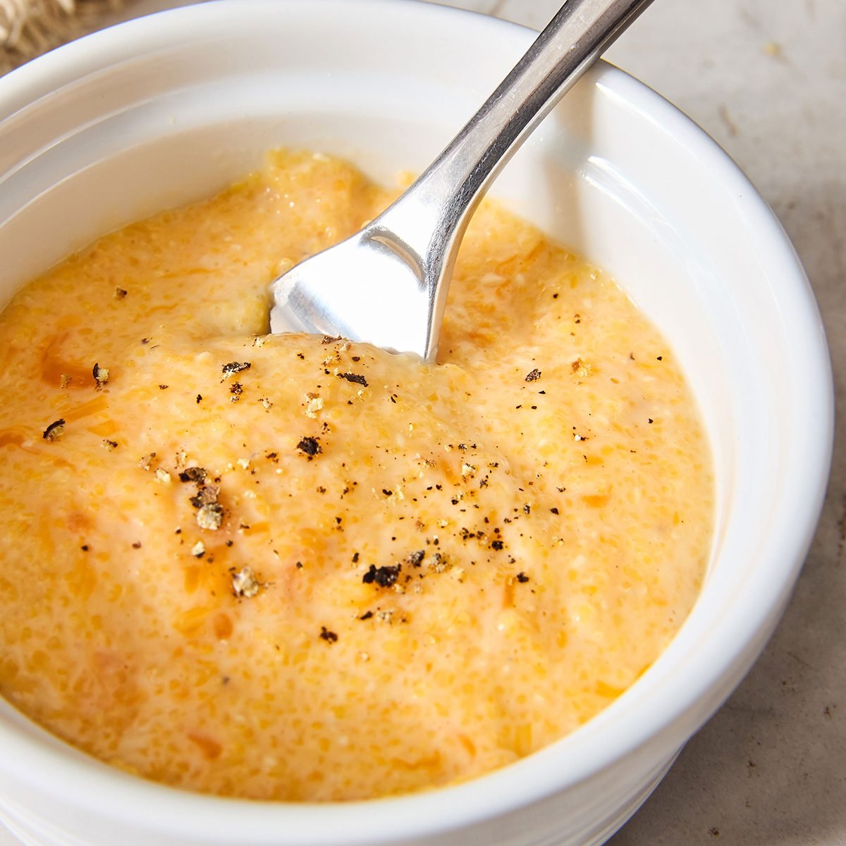 Close up of cheese grits in bowl with fresh pepper on top