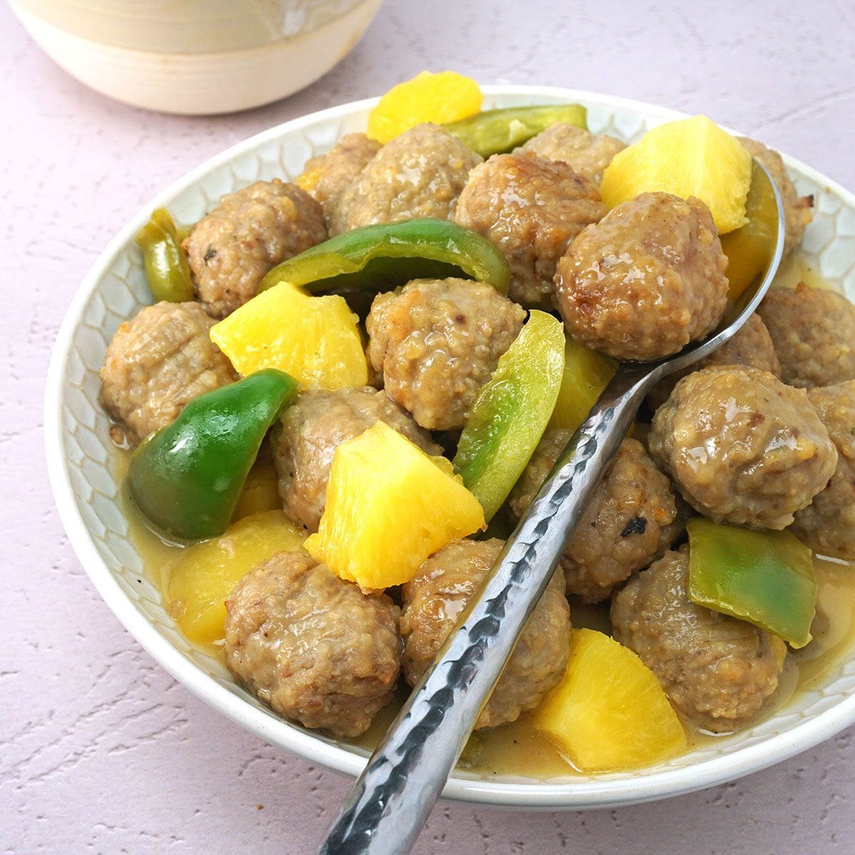 slow cooker sweet and sour meatballs in a serving bowl with a spoon and a side of rice for Taste of Home RMS 27421