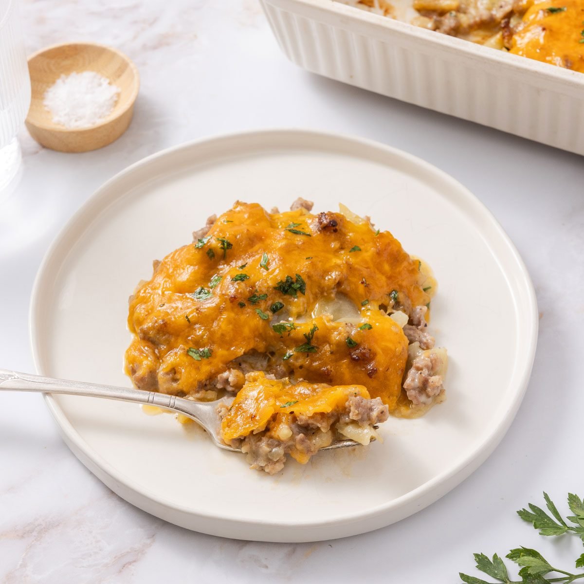 Casserole served in white plate with aking dish next to it.