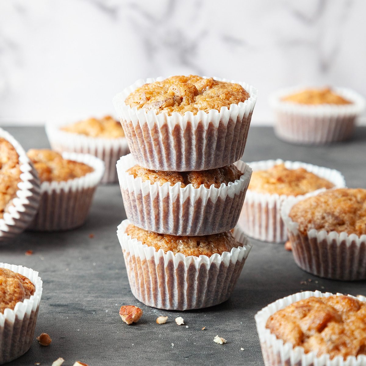 Exps Tohd24 7644 Full yield of Taste of Home Pecan Pie Muffins on a black surface, scattered with pecan pieces 5