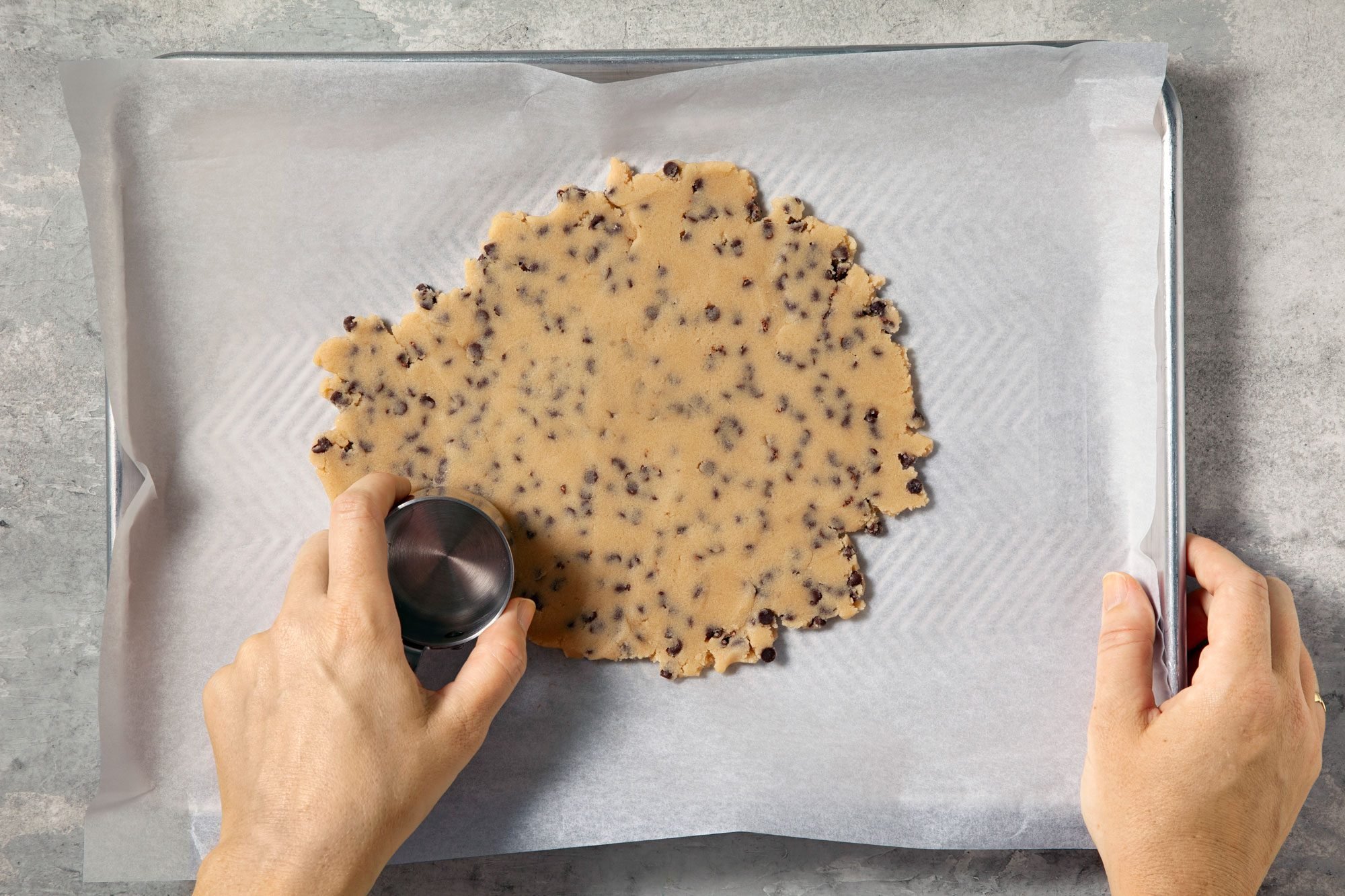 overhead shot; grey background; Pressing into a pan lined with parchment to 1/2 inch thick;