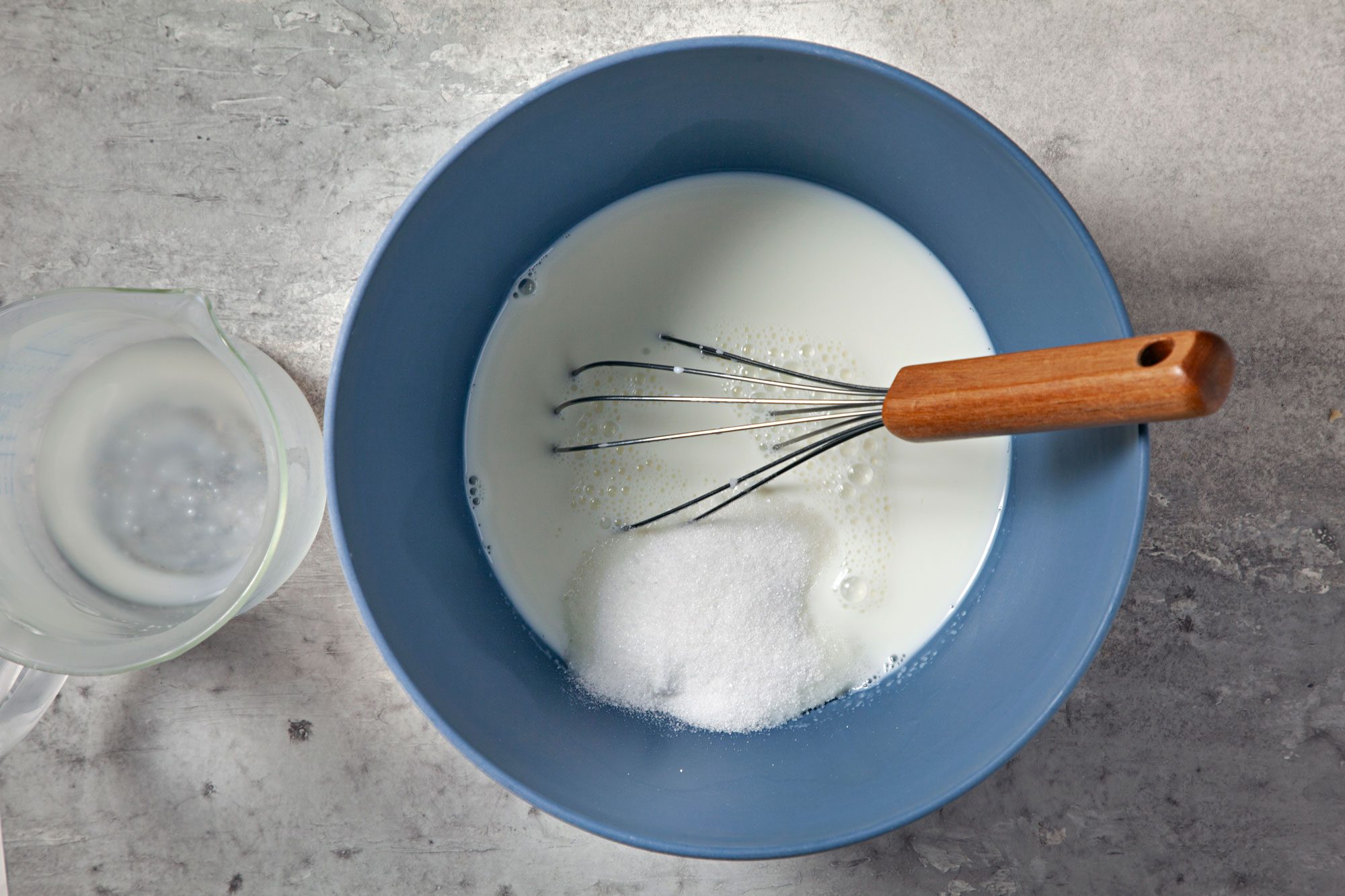 overhead shot; grey background; In a large bowl, whisking milk and sugar;