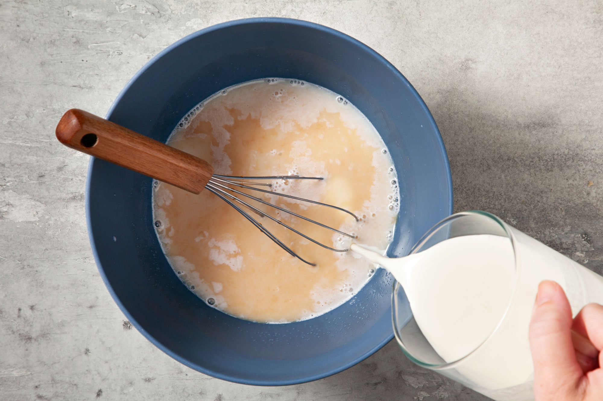 overhead shot; grey background; adding cream, Whisking in cream and vanilla in same bowl;