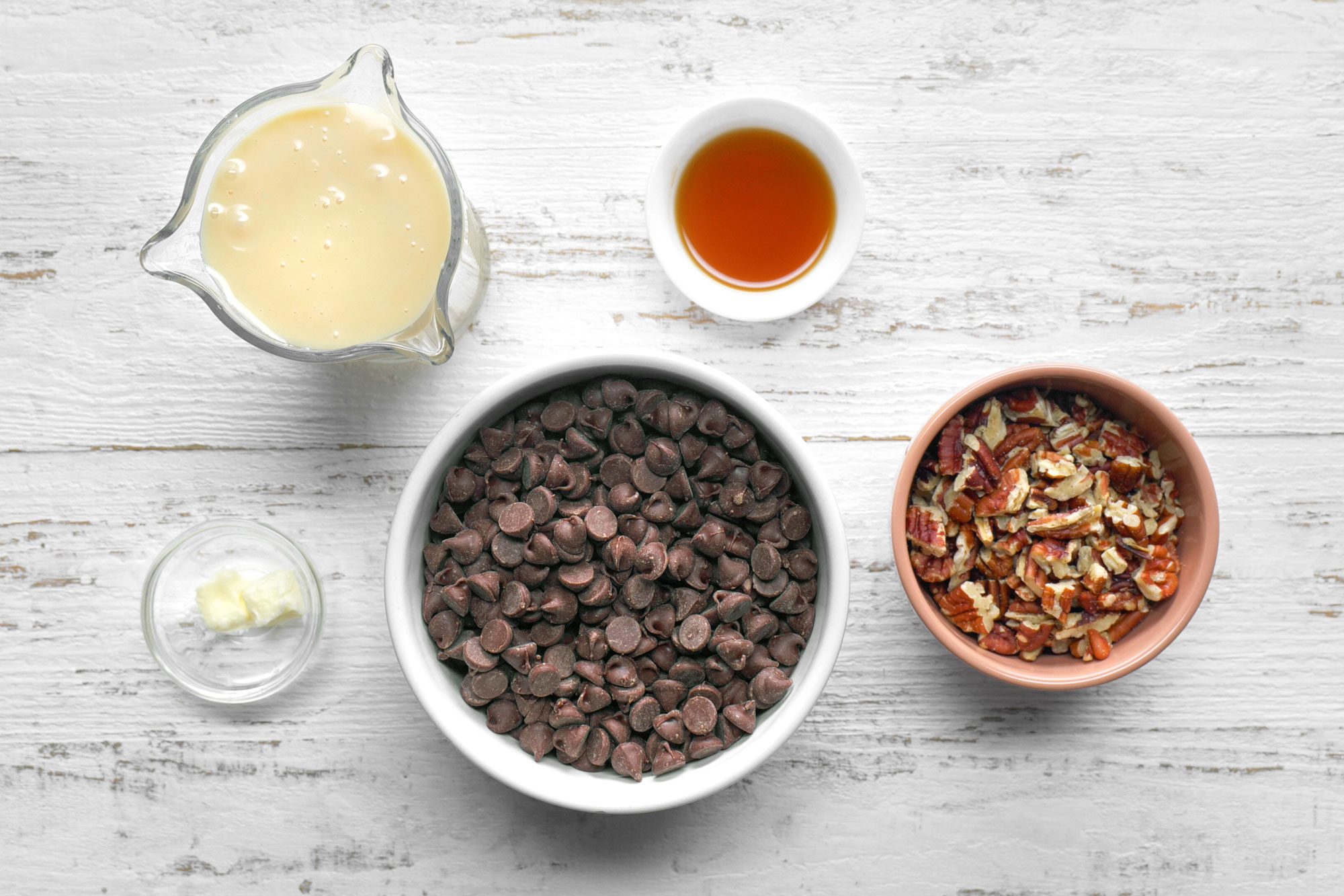 overhead shot; white wooden background; Chocolate Pecan Fudge ingredients placed over wooden background;