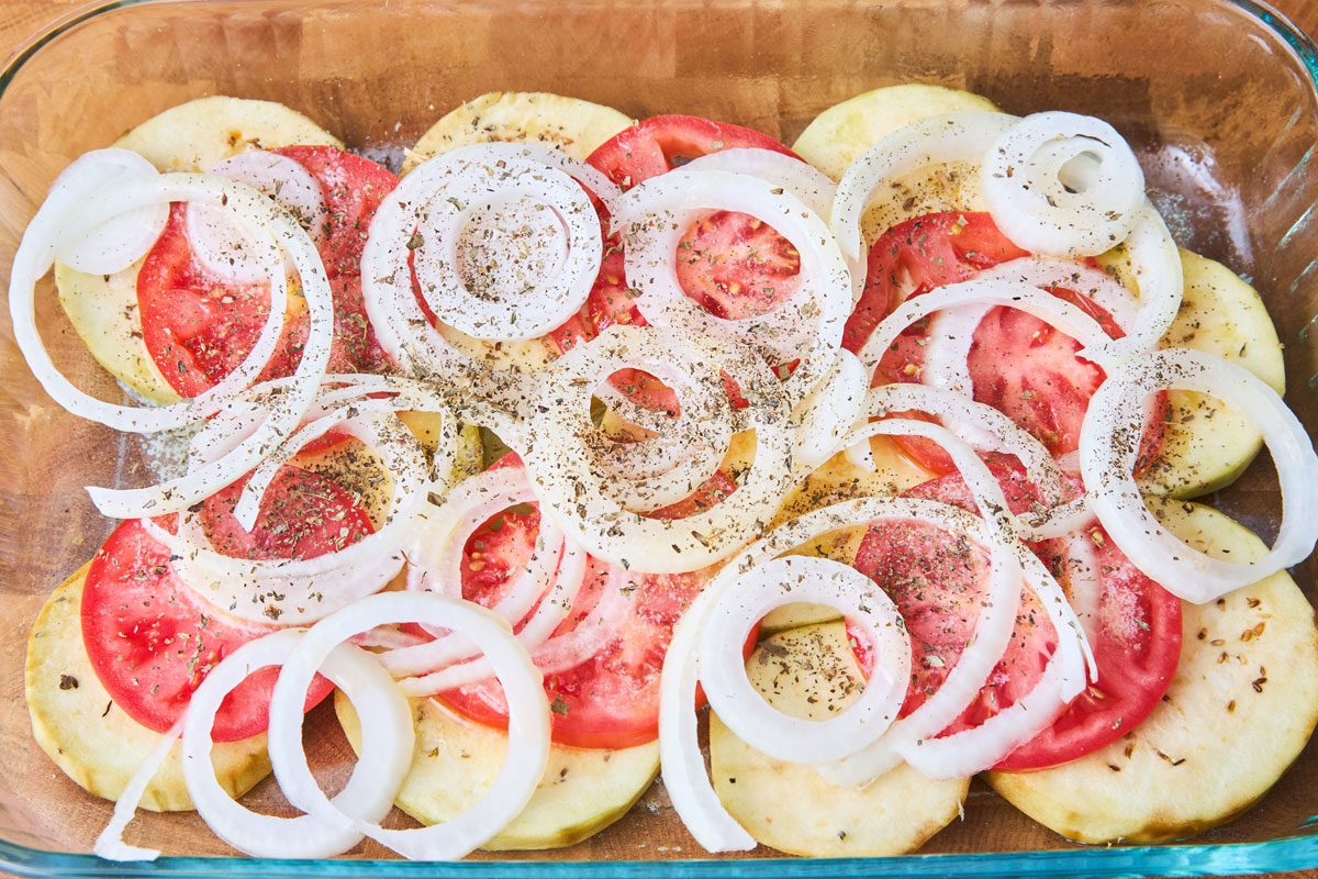 Eggplant, tomatoes and onions layered in a casserole dish with spices.