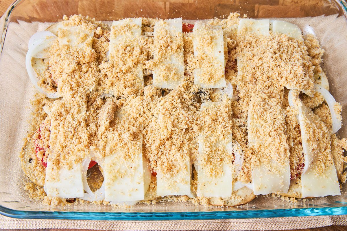 Eggplant casserole ingredients with cheese and breadcrumbs on top in dish