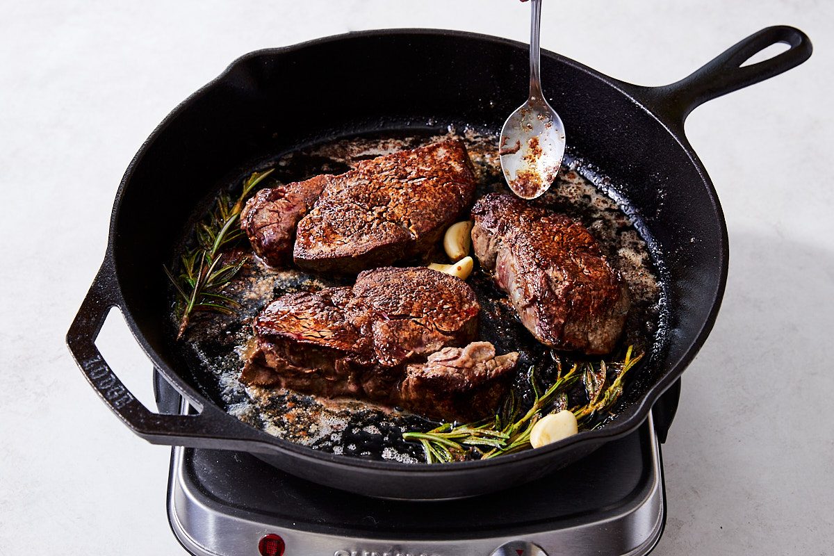 Filet Mignon Step 4- steaks cooked on both sides, garlic, butter and rosemary in skillet, basting with butter