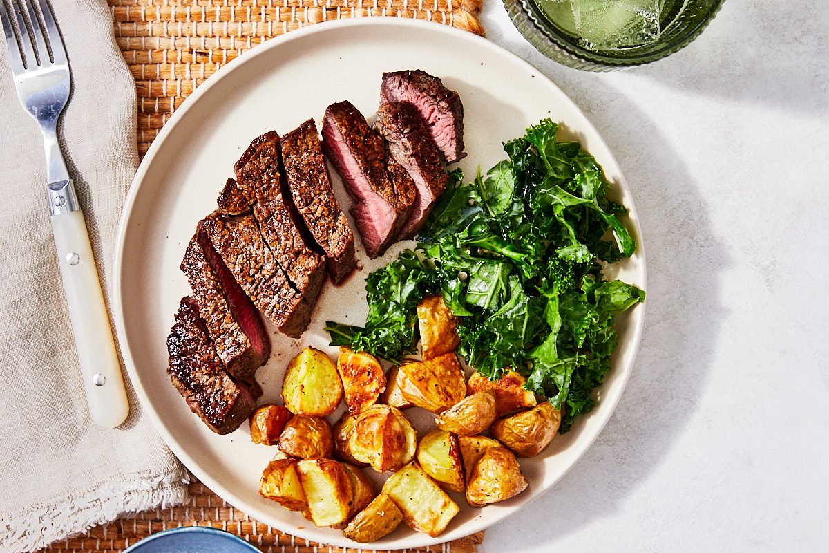 Filet Mignon Hero- steak sliced and plated with greens and roasted potatoes