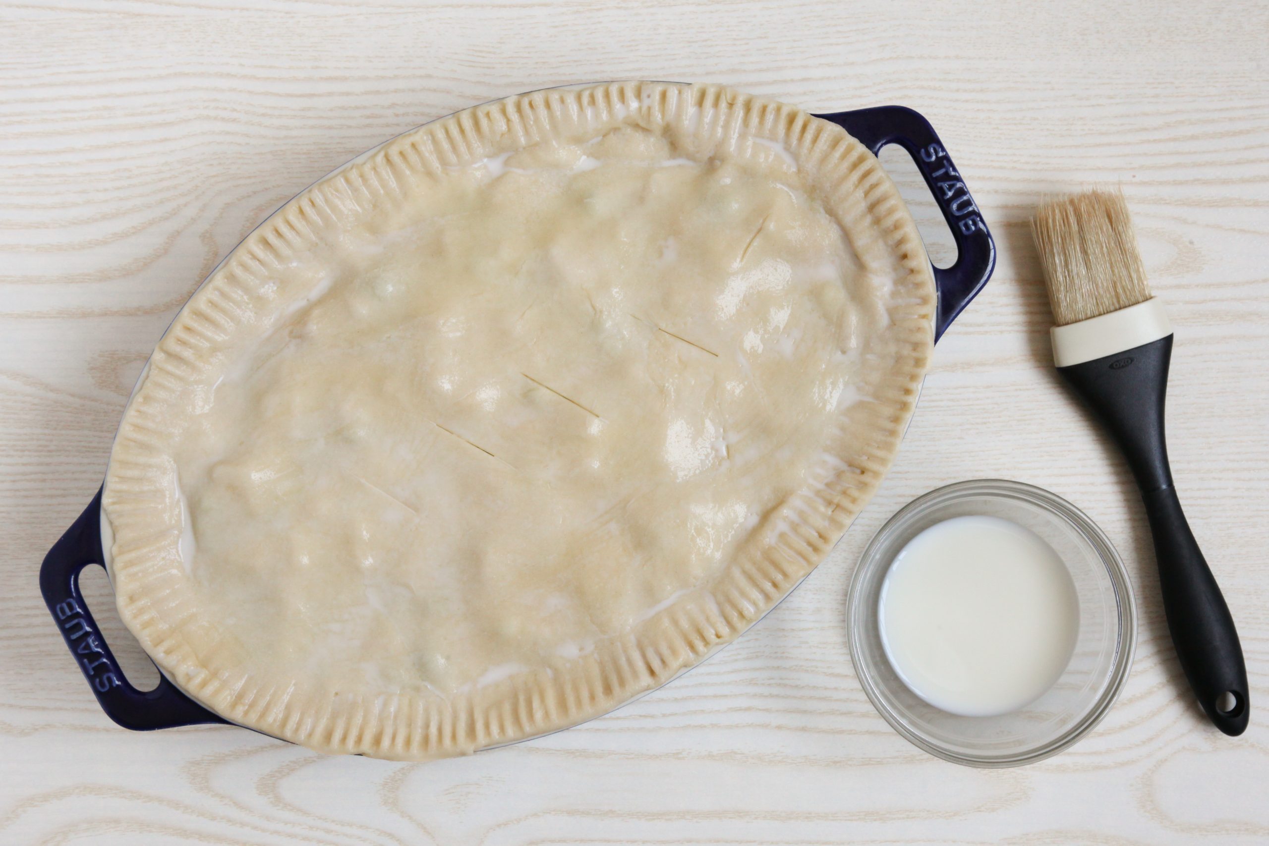 Brushing the top of ham potpie with milk before baking