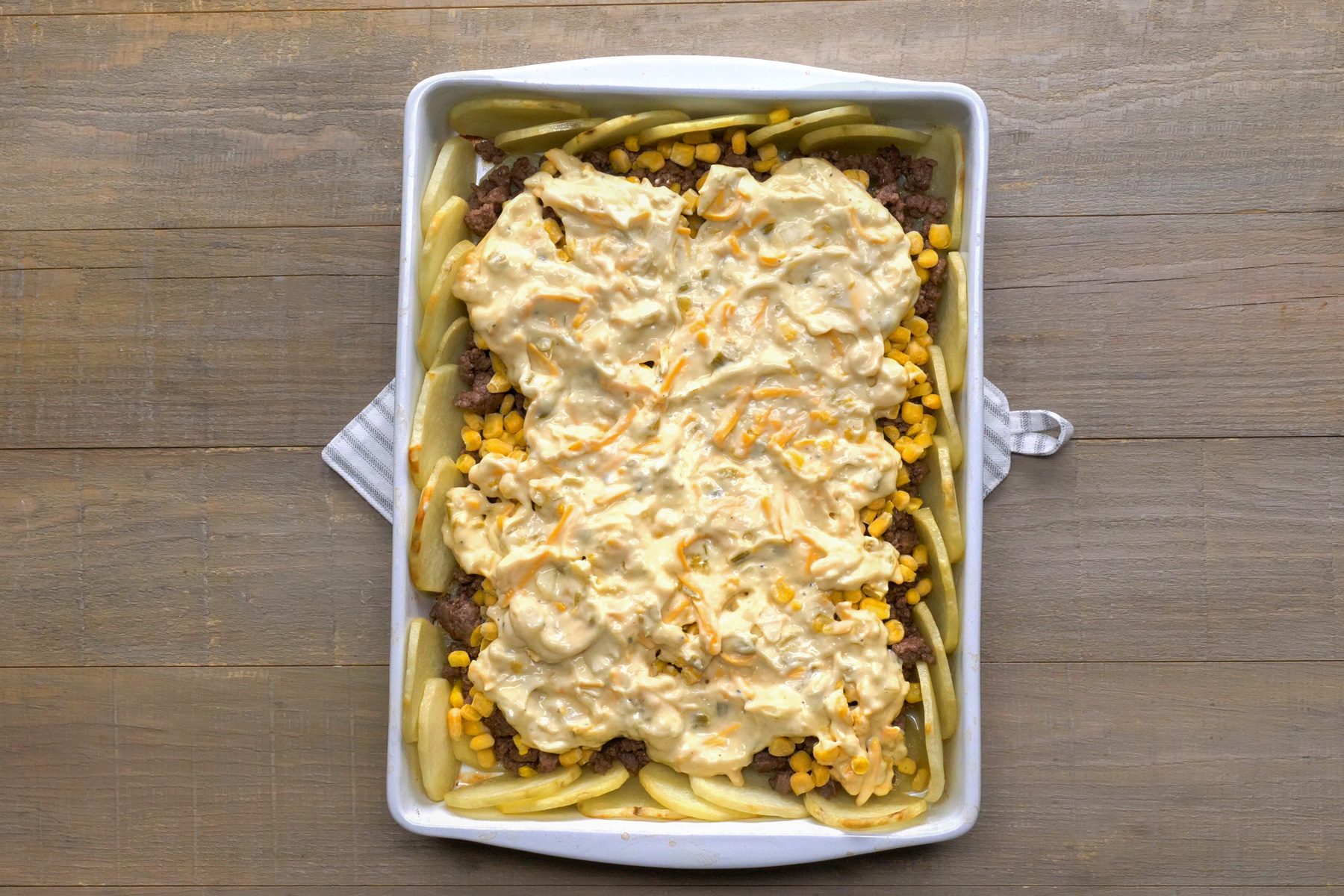 Pouring mixture over beef in baking tray top view shot