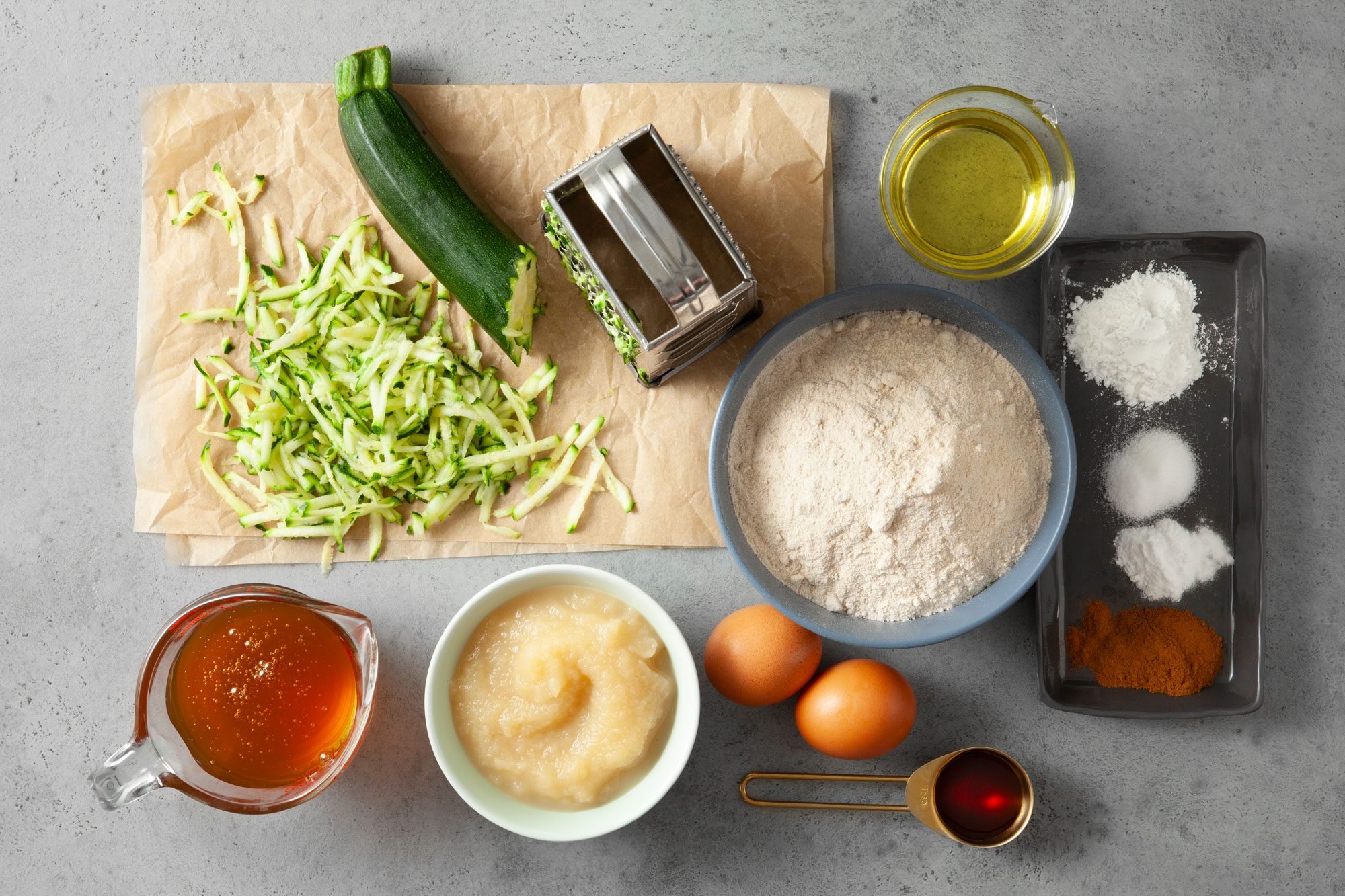 overhead shot of ingredients for Healthy Zucchini Muffins; grey background;